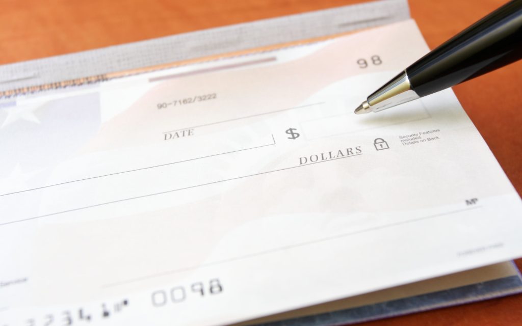 Accepting checks as a nonprofit Closeup of a blank paper check with a pen poised over the amount line