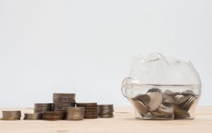 Coins on a table and inside a transparent piggy bank