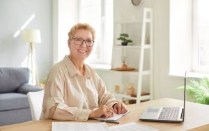 A woman working on a computer in a bright living room.