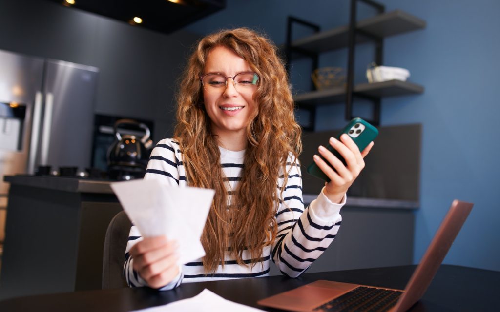 A woman holding receipts and a phone